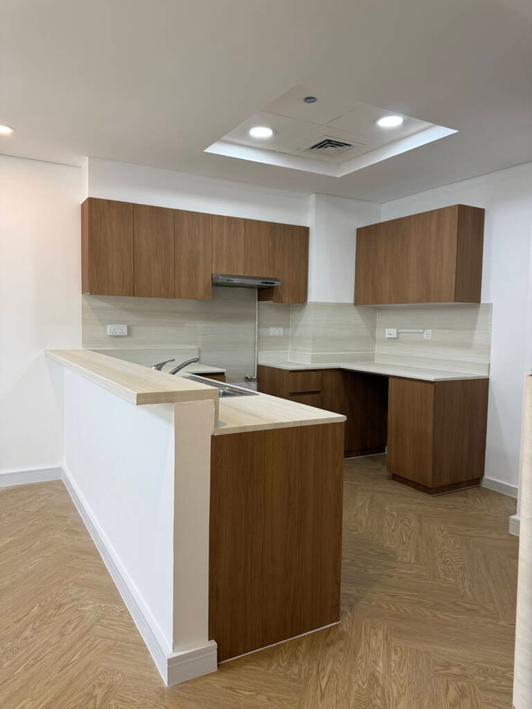Modern kitchen vinyl wrapping in Dubai with premium wood finish cabinets and countertops