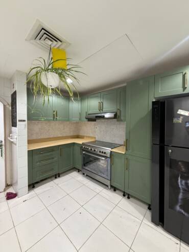Green kitchen cabinets with a modern vinyl wrapping finish in Dubai