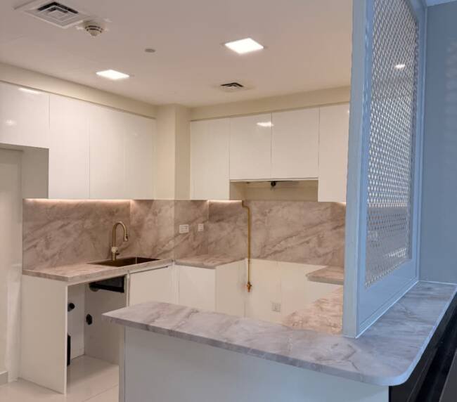 White kitchen cabinets with marble-effect vinyl wrapping in Dubai